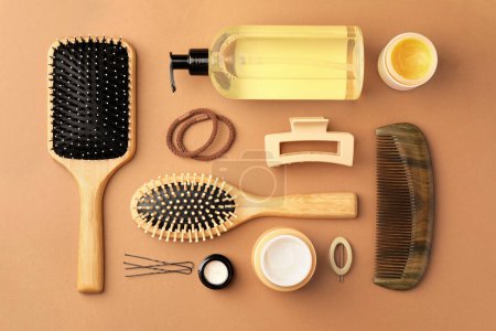 Flat lay composition with wooden hairbrushes and different cosmetic products on light brown background