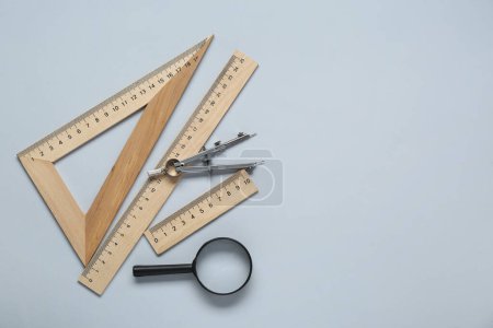 Photo for Different rulers, magnifying glass and compass on light grey background, flat lay. Space for text - Royalty Free Image