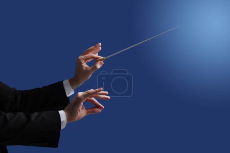 Professioneller Dirigent mit Taktstock auf blauem Hintergrund, Nahaufnahme