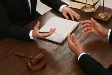 Law and justice. Lawyers having discussion at wooden table, closeup