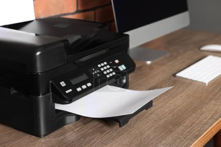 Téléchargez les photos : Imprimante moderne avec papier près de l'ordinateur sur bureau en bois à la maison - en image libre de droit