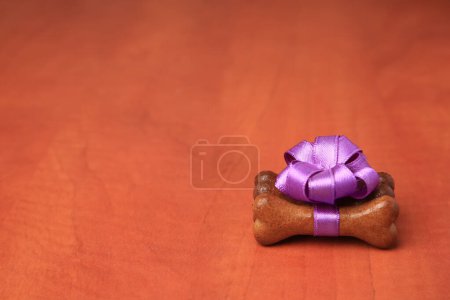 Téléchargez les photos : Cookies pour chien en forme d'os avec noeud violet sur fond en bois, espace pour le texte - en image libre de droit