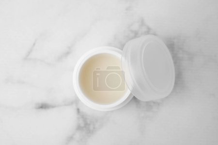 Jar of petroleum jelly on light gray marble table, top view