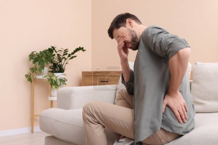 Homme souffrant de douleur dans le dos à la maison, espace pour le texte. Symptômes arthritiques