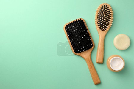 Téléchargez les photos : Brosses à cheveux en bois et différents produits cosmétiques sur fond turquoise, pose plate. Espace pour le texte - en image libre de droit