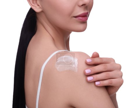 Woman with smear of body cream on her shoulder against white background, closeup