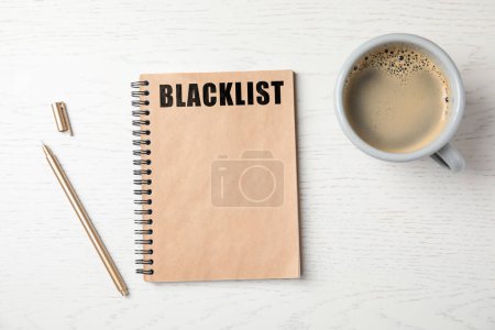 Téléchargez les photos : Word Blacklist écrit dans un bloc-notes, un stylo et un café sur une table en bois blanc, à plat - en image libre de droit