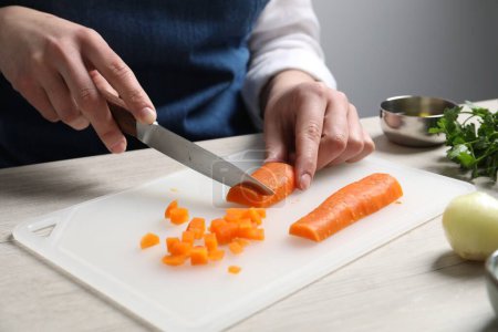 Foto de Mujer cortando zanahoria hervida en la mesa de madera blanca, primer plano. Ensalada de vinagreta para cocinar - Imagen libre de derechos