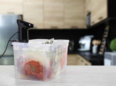 Sous-vide-Kocher und vakuumverpackte Lebensmittel in Schachteln auf Holztischen in der Küche, Platz für Text. Thermische Tauchzirkulation