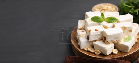 Photo for Pieces of delicious nutty nougat on gray wooden table, space for text. Banner design - Royalty Free Image