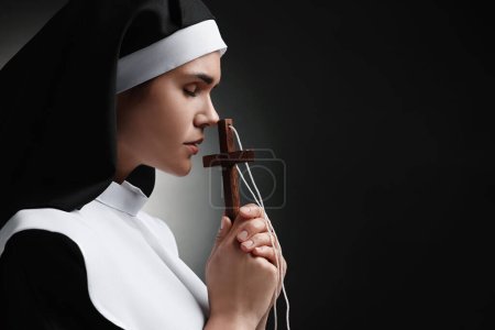 Foto de Monja con cruz orando a Dios sobre fondo negro. Espacio para texto - Imagen libre de derechos