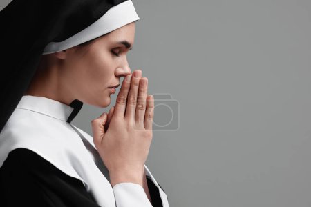 Téléchargez les photos : Nonne avec les mains jointes priant Dieu sur fond gris. Espace pour le texte - en image libre de droit