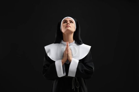 Foto de Monja con las manos cerradas rezando a Dios sobre fondo negro - Imagen libre de derechos