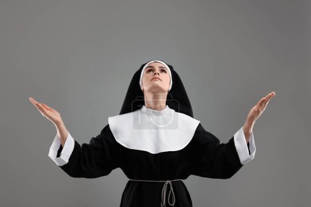 Téléchargez les photos : Nonne priant Dieu sur fond gris - en image libre de droit