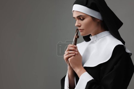 Photo for Nun with cross praying to God on grey background. Space for text - Royalty Free Image