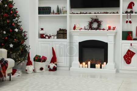 Foto de Acogedora habitación con chimenea y velas encendidas. Ambiente navideño - Imagen libre de derechos