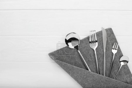 Stylish shiny cutlery set on white wooden table, flat lay. Space for text-stock-photo