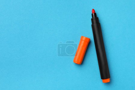Photo for Bright orange marker on light blue background, flat lay. Space for text - Royalty Free Image