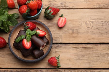 Foto de Deliciosos bocadillos de cuajada esmaltada con fresas frescas y menta en la mesa de madera, la puesta plana. Espacio para texto - Imagen libre de derechos