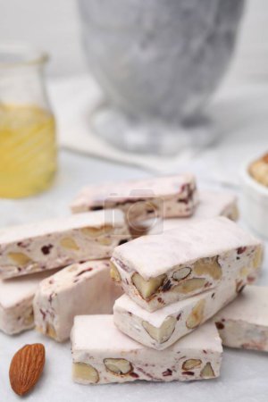 Photo for Pieces of delicious nutty nougat on white table, closeup - Royalty Free Image