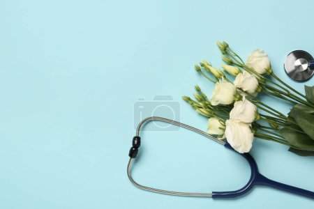 Stethoscope and beautiful eustoma flowers on light blue background, flat lay with space for text. Happy Doctor's Day