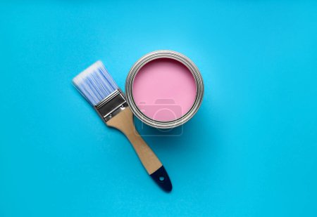 Canette avec peinture rose et pinceau sur fond bleu clair, pose plate