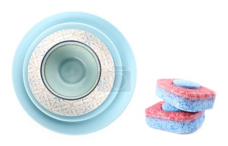 Foto de Comprimidos para lavavajillas y pila de vajilla limpia aislada en blanco - Imagen libre de derechos