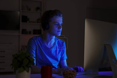 Teenage boy using computer in bedroom at night. Internet addiction Poster 658402644