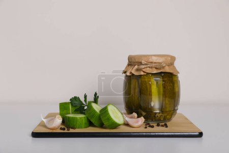 Foto de Sabrosos pepinos en escabeche, verduras cortadas y ajo en la mesa blanca - Imagen libre de derechos