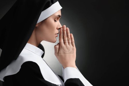 Foto de Monja con las manos cerradas rezando a Dios sobre fondo negro. Espacio para texto - Imagen libre de derechos