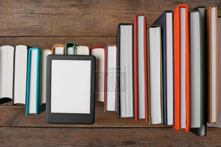Foto de Lector de libros electrónicos portátil en libros de tapa dura sobre mesa de madera, disposición plana - Imagen libre de derechos
