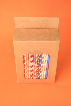 Photo for Box with many paper drinking straws on orange background - Royalty Free Image