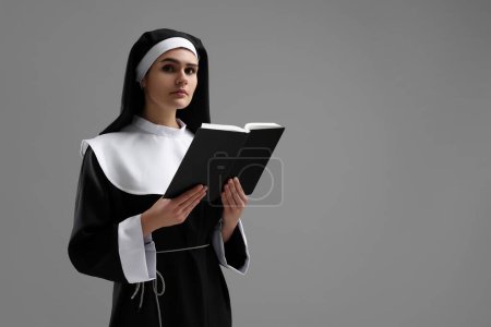 Téléchargez les photos : Nonne avec Bible sur fond gris, espace pour le texte - en image libre de droit