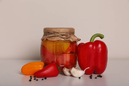 Foto de Sabrosos pimientos en escabeche, verduras frescas y ajo en la mesa blanca - Imagen libre de derechos