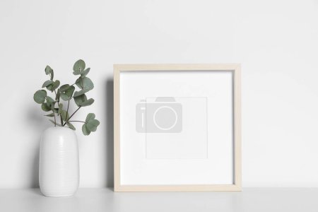 Photo for Empty photo frame and vase with decorative eucalyptus leaves on white table. Mockup for design - Royalty Free Image