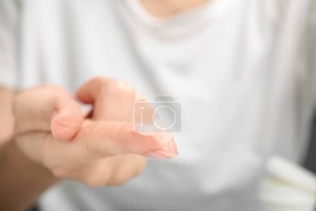Femme avec un échantillon de pétrolatum cosmétique sur le doigt, gros plan. Espace pour le texte