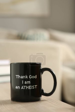 Foto de Copa con frase Gracias a Dios que soy ateo en mesa de madera - Imagen libre de derechos