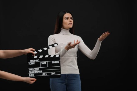 Foto de Actriz actuando mientras la segunda cámara asistente sostiene el clapperboard sobre fondo negro. Industria cinematográfica - Imagen libre de derechos