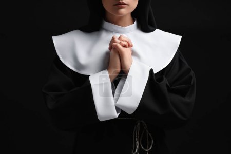 Foto de Monja con las manos cerradas rezando a Dios sobre fondo negro, primer plano - Imagen libre de derechos