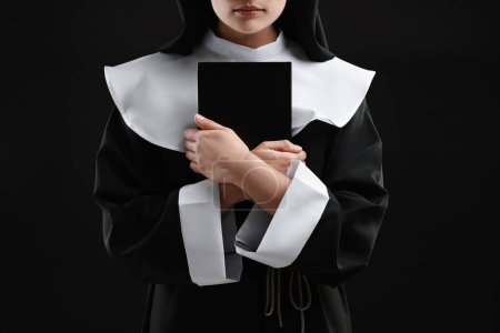 Foto de Monja con Biblia sobre fondo negro, primer plano - Imagen libre de derechos