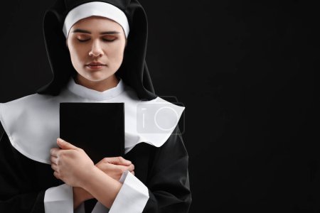 Foto de Monja con Biblia sobre fondo negro, espacio para texto - Imagen libre de derechos