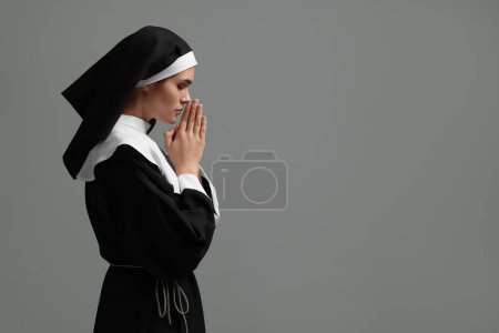 Foto de Monja con las manos cerradas rezando a Dios sobre fondo gris. Espacio para texto - Imagen libre de derechos