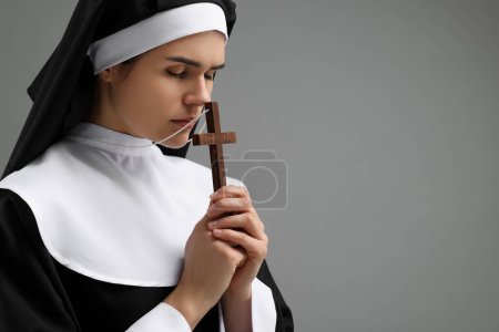 Foto de Monja con cruz orando a Dios sobre fondo gris. Espacio para texto - Imagen libre de derechos