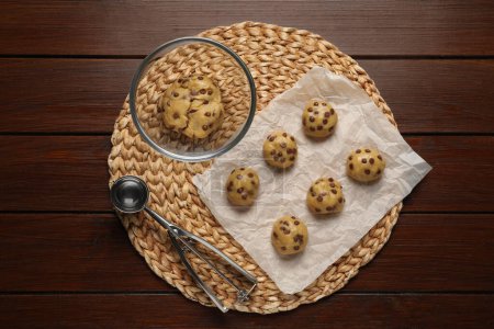 Téléchargez les photos : Pâte fraîche et biscuits aux pépites de chocolat non cuits sur table en bois, vue de dessus - en image libre de droit