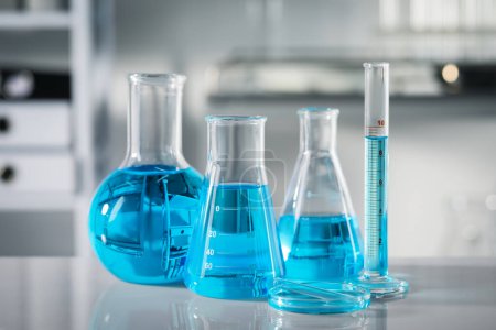 Foto de Diferentes cristalería con líquido azul claro en la mesa en el laboratorio - Imagen libre de derechos