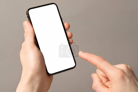 Foto de Hombre sosteniendo teléfono inteligente con pantalla en blanco sobre fondo gris claro, primer plano. Burla para el diseño - Imagen libre de derechos