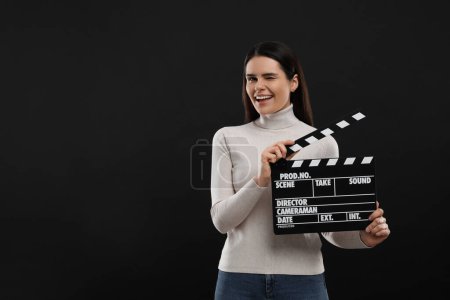 Foto de Feliz actriz con clapperboard sobre fondo negro, espacio para el texto. Industria cinematográfica - Imagen libre de derechos