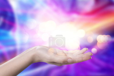 Foto de Fenómenos Aura. Mujer con luces de energía saliendo de su mano contra el fondo de color, primer plano - Imagen libre de derechos