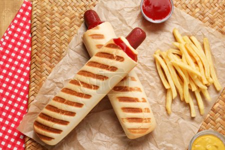 Téléchargez les photos : Délicieux hot-dog français, frites et sauce trempette sur tapis en osier, pose à plat - en image libre de droit