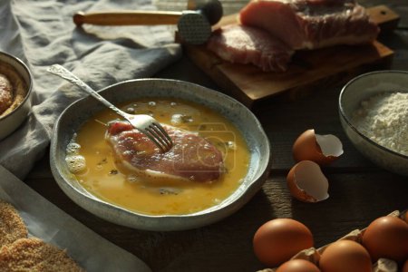 Téléchargez les photos : Schnitzel de cuisine. côtelette de porc cru dans les œufs, le maillet de viande et les ingrédients sur la table en bois - en image libre de droit